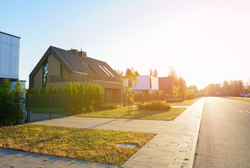 Modern luxury Villa. Street Road in Contemporary Residence with Barnhouse. Modern Barn house. Barn home with lawn, shrubs, green courtyard in sustainable enviroment. Family House in Gated Community.