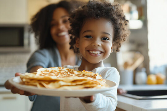 Smiling child presenting a plate of pancakes in a bright kitchen, mother in the background sharing a moment of pride and warmth - Powered by Adobe