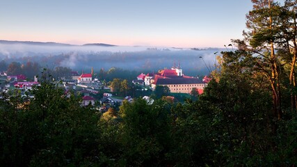 View of Zelív illuminated by the morning sun, foggy, monastery