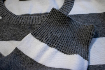 Close-up of cozy knitted gray and white striped sweater fabric, showcasing texture and craftsmanship. Perfect for fashion and textile themes.