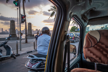 A man rides a scooter down the bay in the City as seen from the back of a taxi