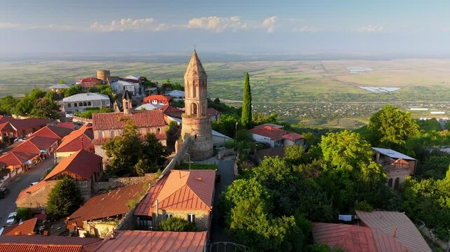 Old Georgian town Signagi in warm sunset lights. Aerial view of Signagi city center and Alazani Valley in the background. Kakheti Region, Georgia