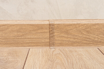 Plastic skirting board with wood texture. Floor skirting board connector