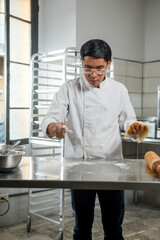 Pastry chef places flour on a steel table so that the dough does not stick and the process is...
