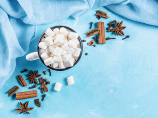 Marshmallows and winter spices on blue background with copyspace. Flat lay or top view. Background...
