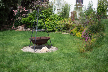 Garden scene with fire pit and tripod surrounded by greenery