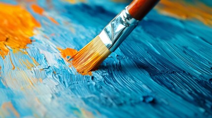 Obraz premium Close-up of a paintbrush applying vibrant blue and orange oil paint on a textured canvas