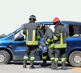 Firefighters use powerful hydraulic shears to rip off the doors of a crashed car freeing an injured person after a highway accident