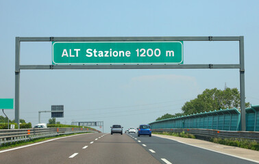 highway sign with large text ALT STAZIONE which means Stop at toll in 1200 meters away on the...