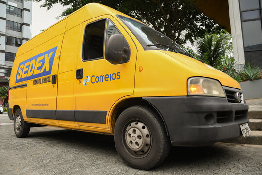 Yellow "Correios" van. Sedex and Correios logo on the car. Correios post office of Brazil logistics warehouse. Mail delivery car parked. 