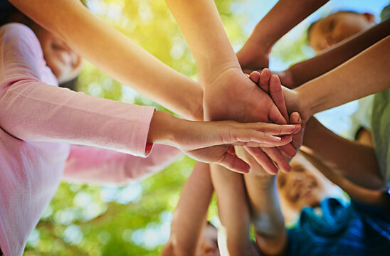 Stack of hands, below and children in nature for unity, support and friendship at academy. Education, community and group of kid students with solidarity and bonding for elementary school scholarship