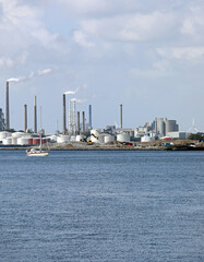 cement factory with tall chimneys puffing out white smoke and seashore during production
