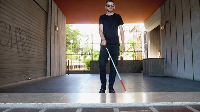 A determined blind man, guided by his cane, confidently approaches and surpasses a step in his path, showcasing his resilience and adaptability in navigating the world around him.