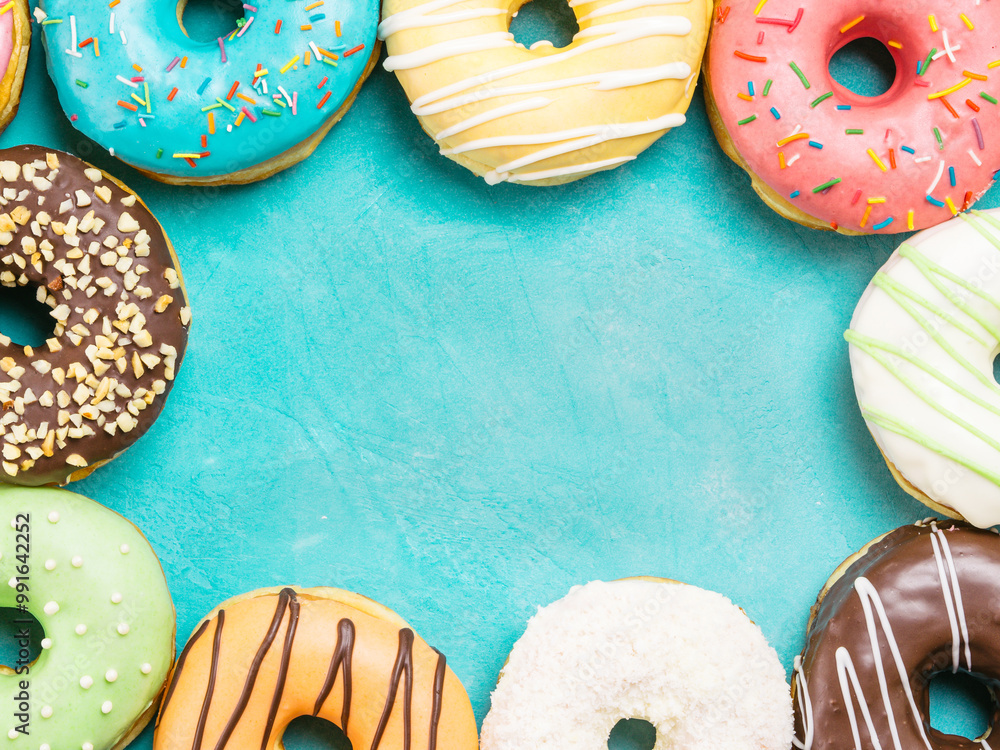 Wall mural Top view of assorted donuts on blue concrete background with copy space. Colorful donuts background. Various glazed doughnuts with sprinkles.