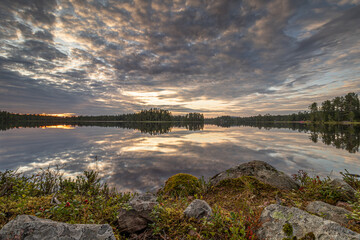 Rocks and heath by a mirror-smooth Swedish lake under an imposing cloud cover. This lake in Orsa Grönklitt, central Sweden, was as smooth as a billiard table. 