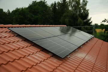 Black solar panels on a red tile roof
