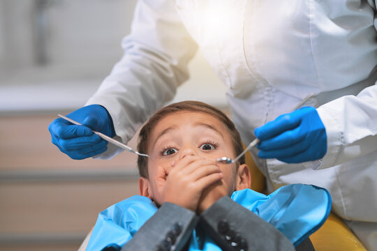 Portrait, dentist and child with anxiety or fear in hospital for procedure, examination or oral care. Person, doctor and covering mouth for hygienist, teeth cleaning or root canal treatment in clinic