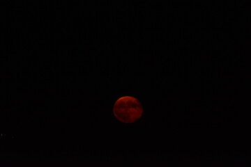 glowing red moon shining against a dark night sky