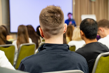 People are sitting in chairs, watching a presentation in front