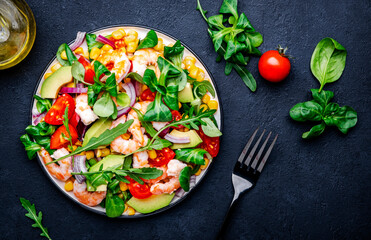 Foodie food salad with shrimps, corn, avocado, tomatoes, lamb lettuce, arugula and red onion on black background. Top  view © 5ph