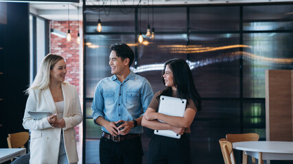 businesspeople discussing papers and working on laptops, indicating active discussion or...