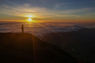 Obraz premium Une personne observe un coucher de soleil au sommet du Mont Pico