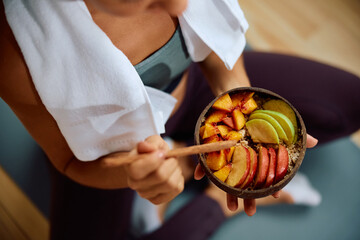 Close up of woman eating fruit salad after exercising.