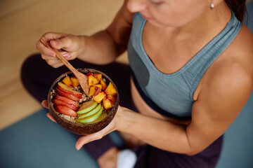 Close up of athletic woman eating mixed fruit after sports training.