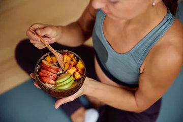 Fotobehang Close up of athletic woman eating mixed fruit after sports training. © Drazen
