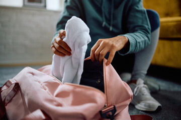 Close up of athlete packing her gym bag for sports training.