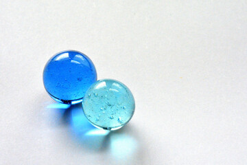 Two vintage glass marbles reflecting light on pure white surface