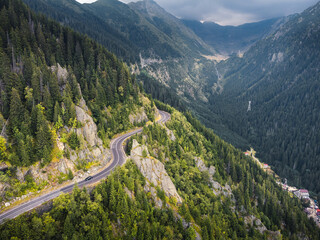 Drone view of a mountain road with moody clouds hovering over the peaks.
