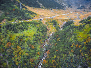 Stunning aerial shot of Romania&rsquo;s Transfagarasan road nestled in green, misty mountains.