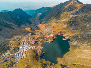 Drone view of the scenic Transfagarasan highway in the fall, capturing cars amid a breathtaking autumn landscape.