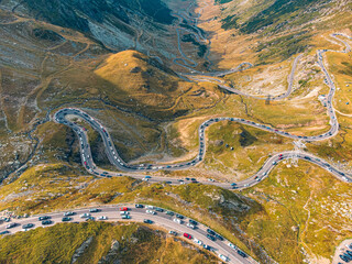 Aerial view of the Transfagarasan highway, highlighting the contrast of cars against the vibrant autumn trees.