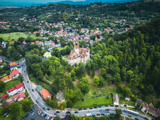  Aerial shot of Bran Castle with the majestic mountains in the background, illustrating its historical significance and scenic beauty.