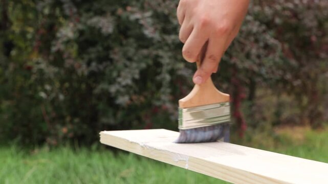The carpenter treats the board with insecticide and applies varnish to the board.