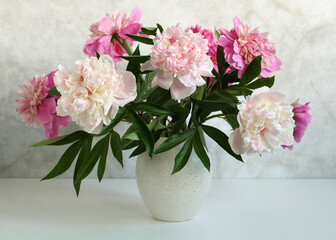 a bouquet of peonies in a vase on the table. pink bright garden flowers. full bloom.