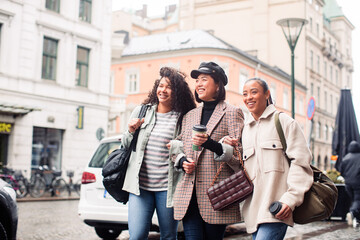 Three diverse female friends walking together on city street