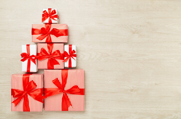 Gift boxes in Christmas tree shape on wooden background, top view