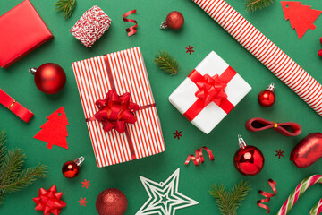 Handmade wrapped christmas gift boxes with stuff on color background, top view