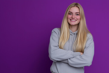Student in hoodie and sweatpants against purple background with confident smile