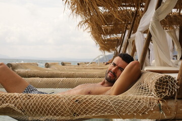 Handsome man lying down on suspended net 