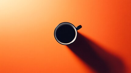 Black coffee mug with dark coffee on orange background.