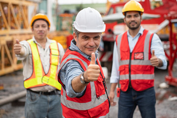 Thump up Mature caucasian engineer man worker  with team and spare crane background