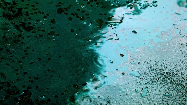 にわか雨がアスファルトや石の硬い地面に降って滴が跳ねる