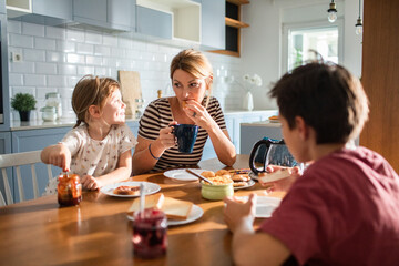 Mother eating breakfast with her kids on kitchen table
