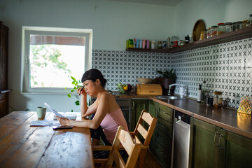 Stressed woman reviewing bills and financial documents at home