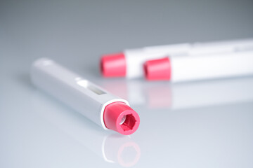 composition with three pen injectors with a red tip for biological treatments such as Adalimumab,...