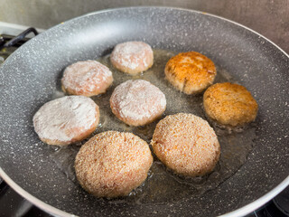  raw meat cutlets are fried in a frying pan in the kitchen